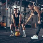 Imagem de uma personal ajudando um aliuno. Como conseguir alunos de Personal Trainer